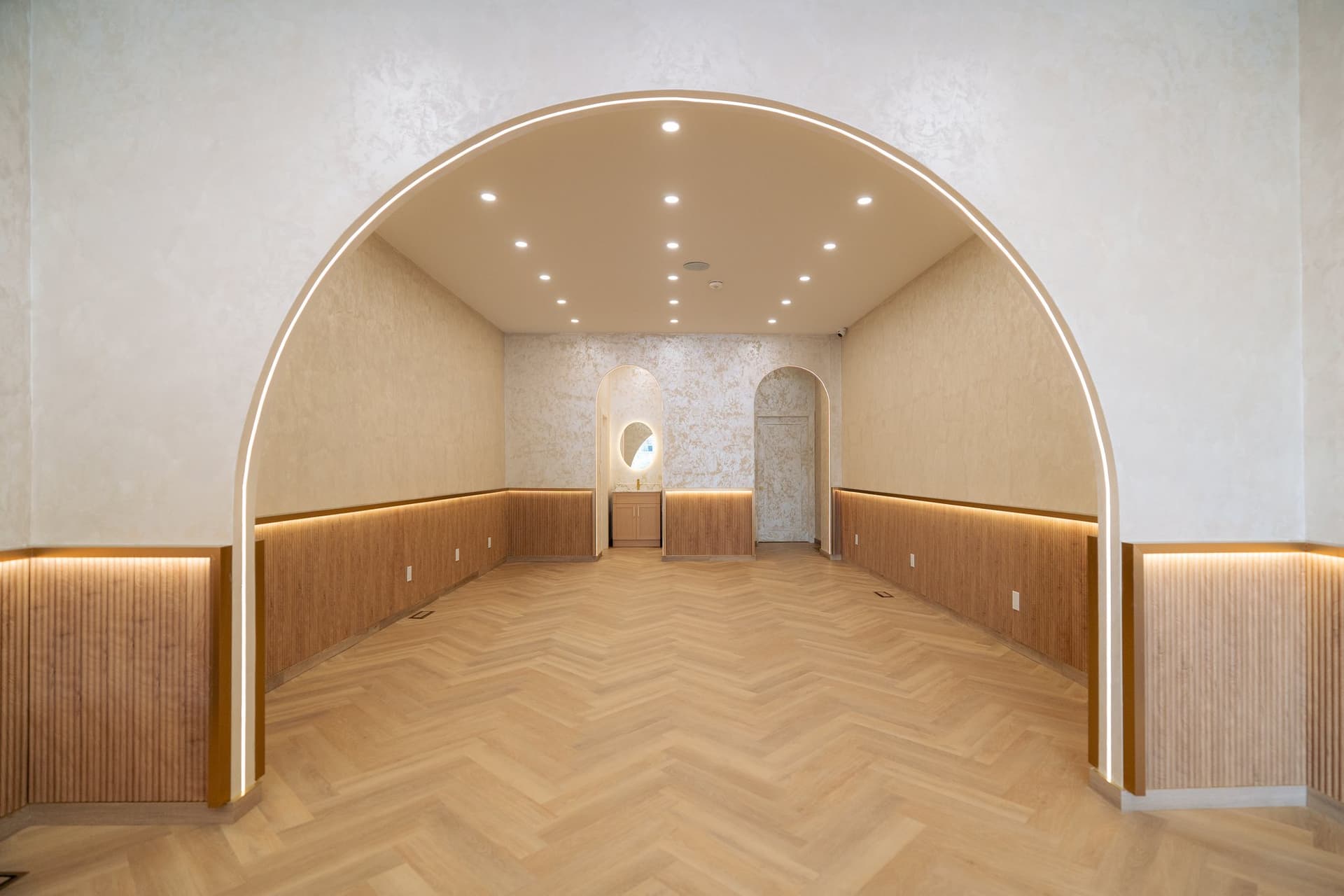 A finished room seen straight on: a plastered barrel arch over a cove-lit oak wainscot
