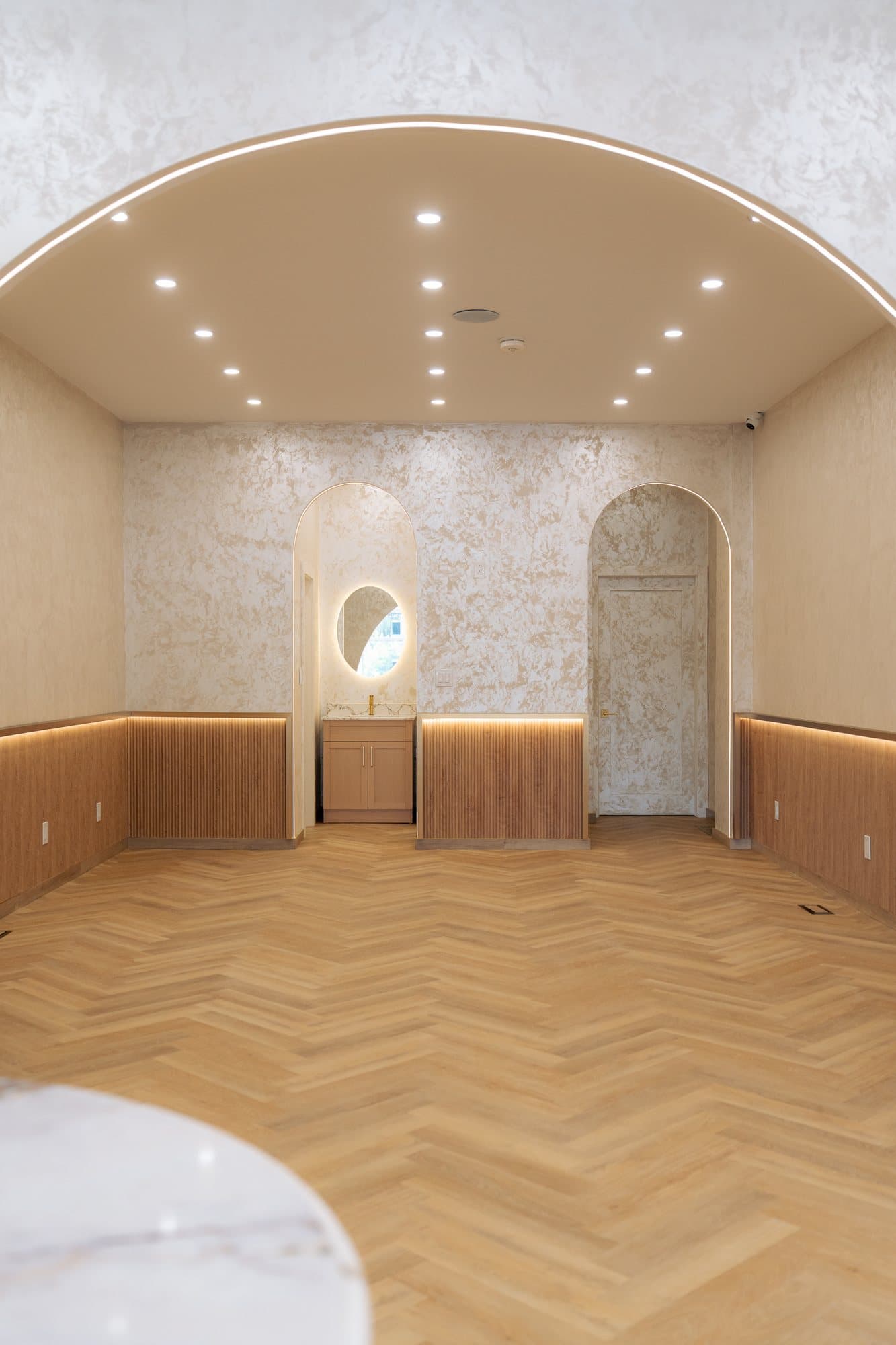 Barrel-vaulted cafe dining room with arched niches and a cove-lit oak wainscot