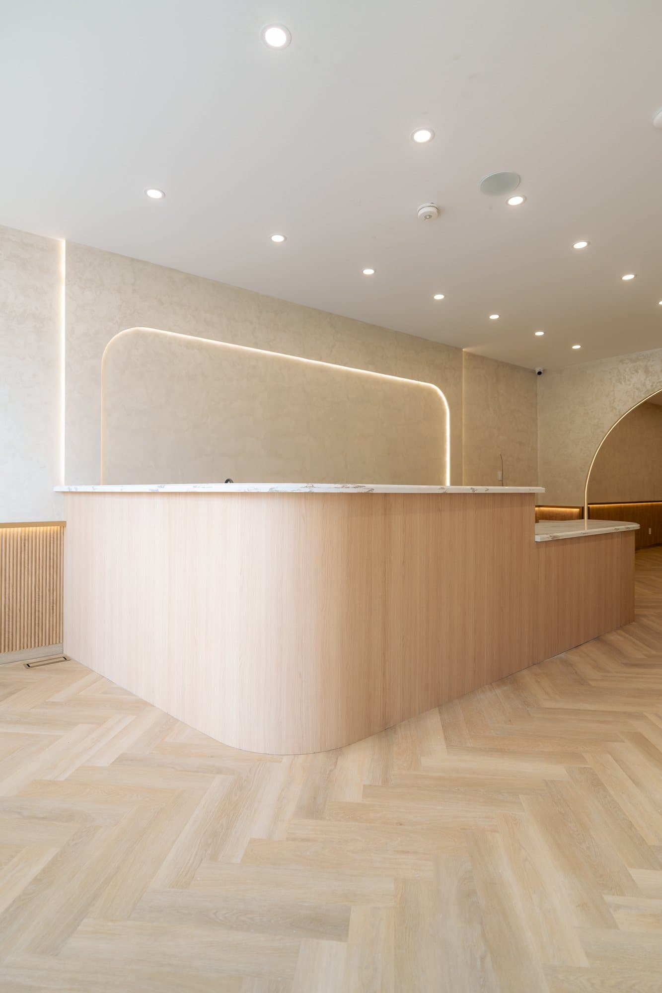 Curved white oak service counter with a marble top in a finished cafe