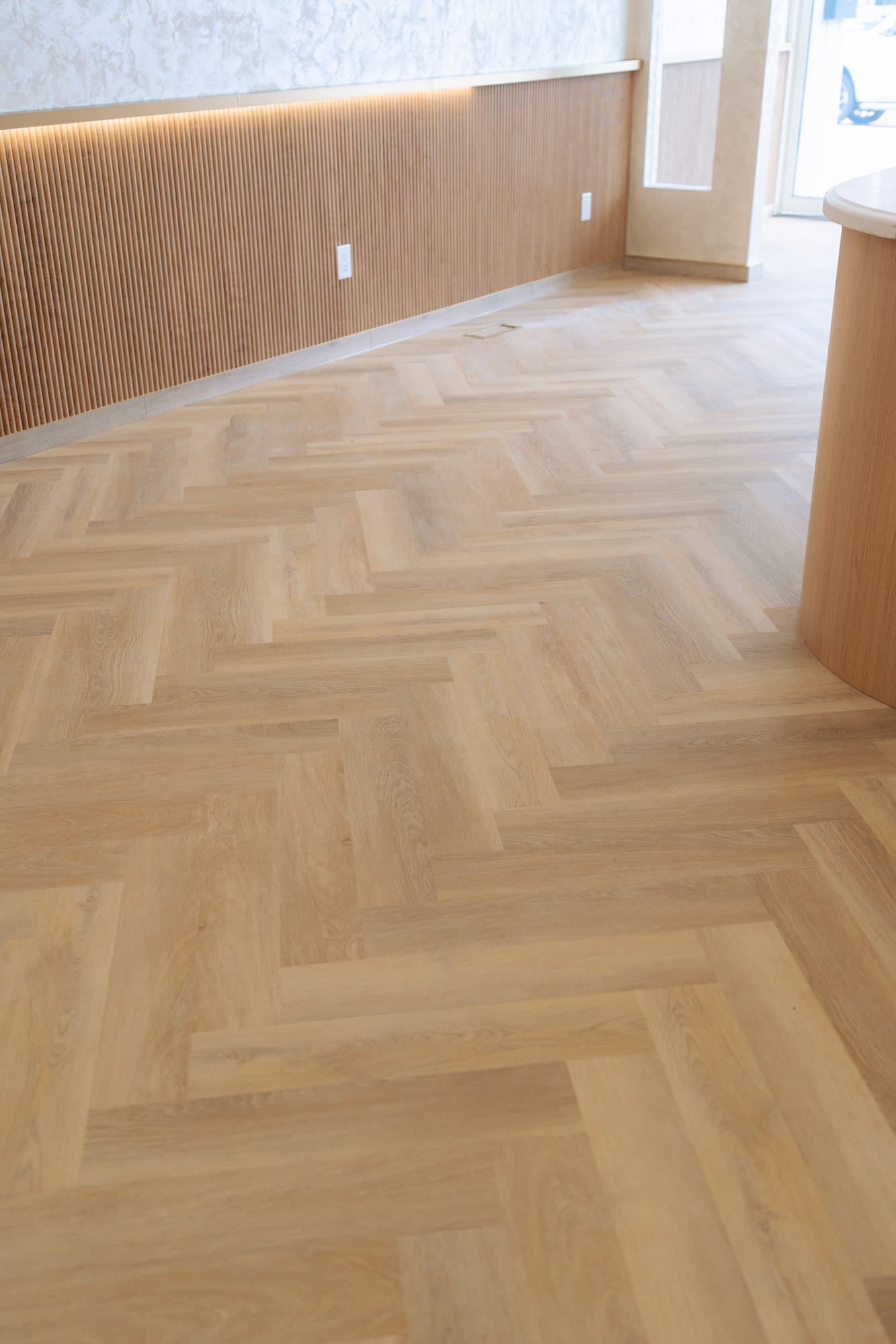 Herringbone floor running the length of a room below a reeded oak wainscot