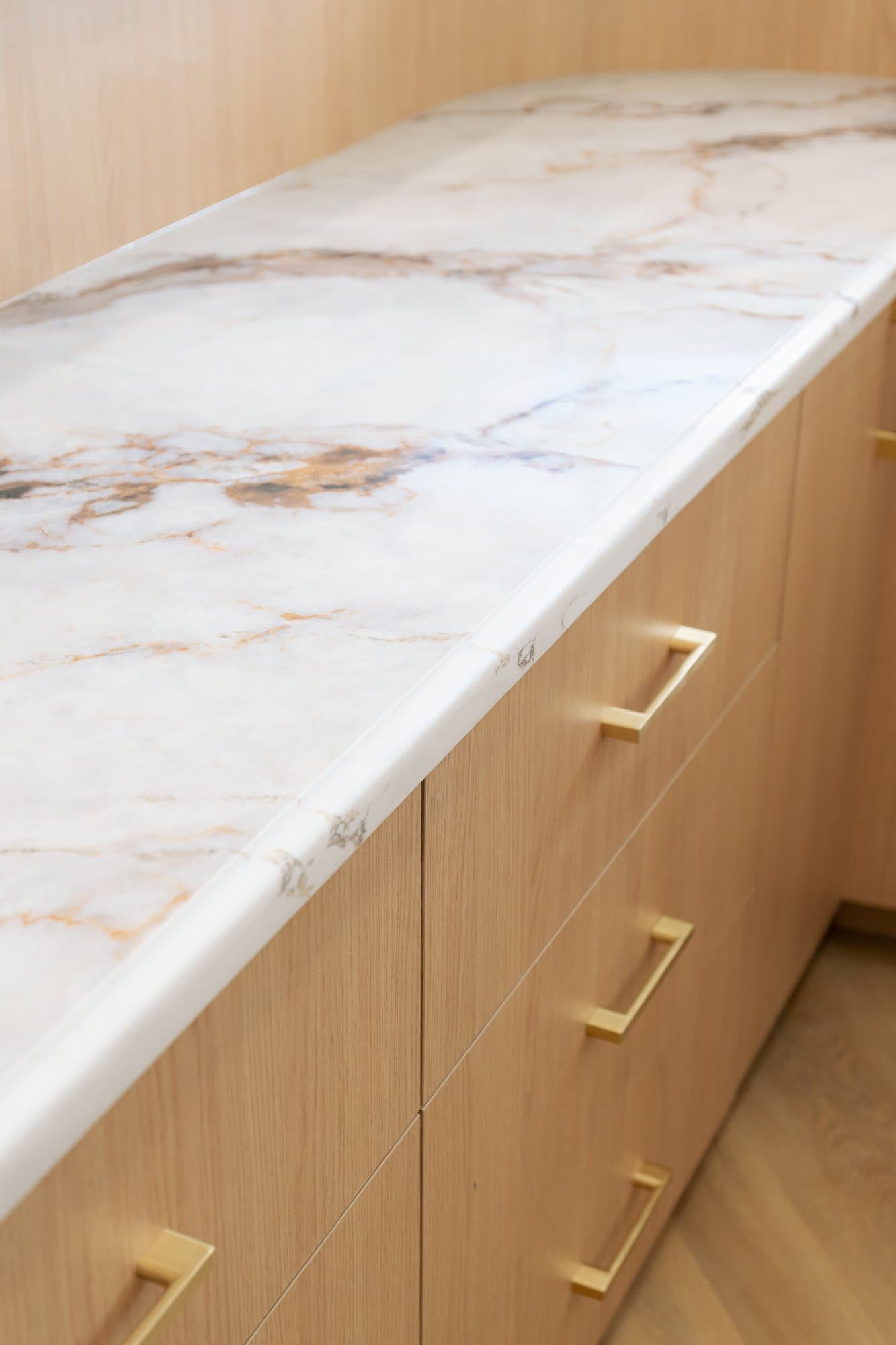 Rust and gold veining running through a marble counter above brass pulls