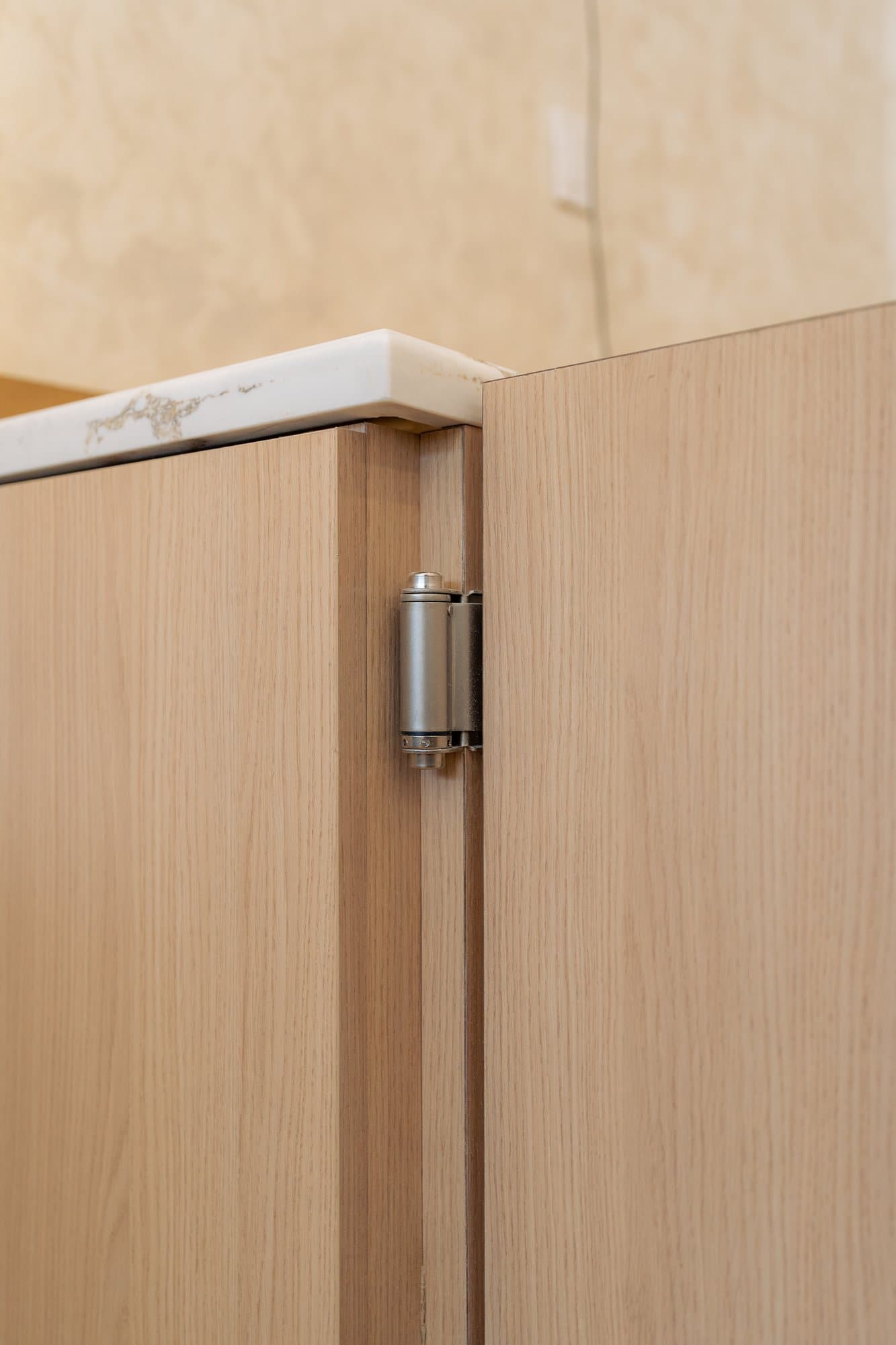 A concealed hinge in the edge of a white oak cabinet door