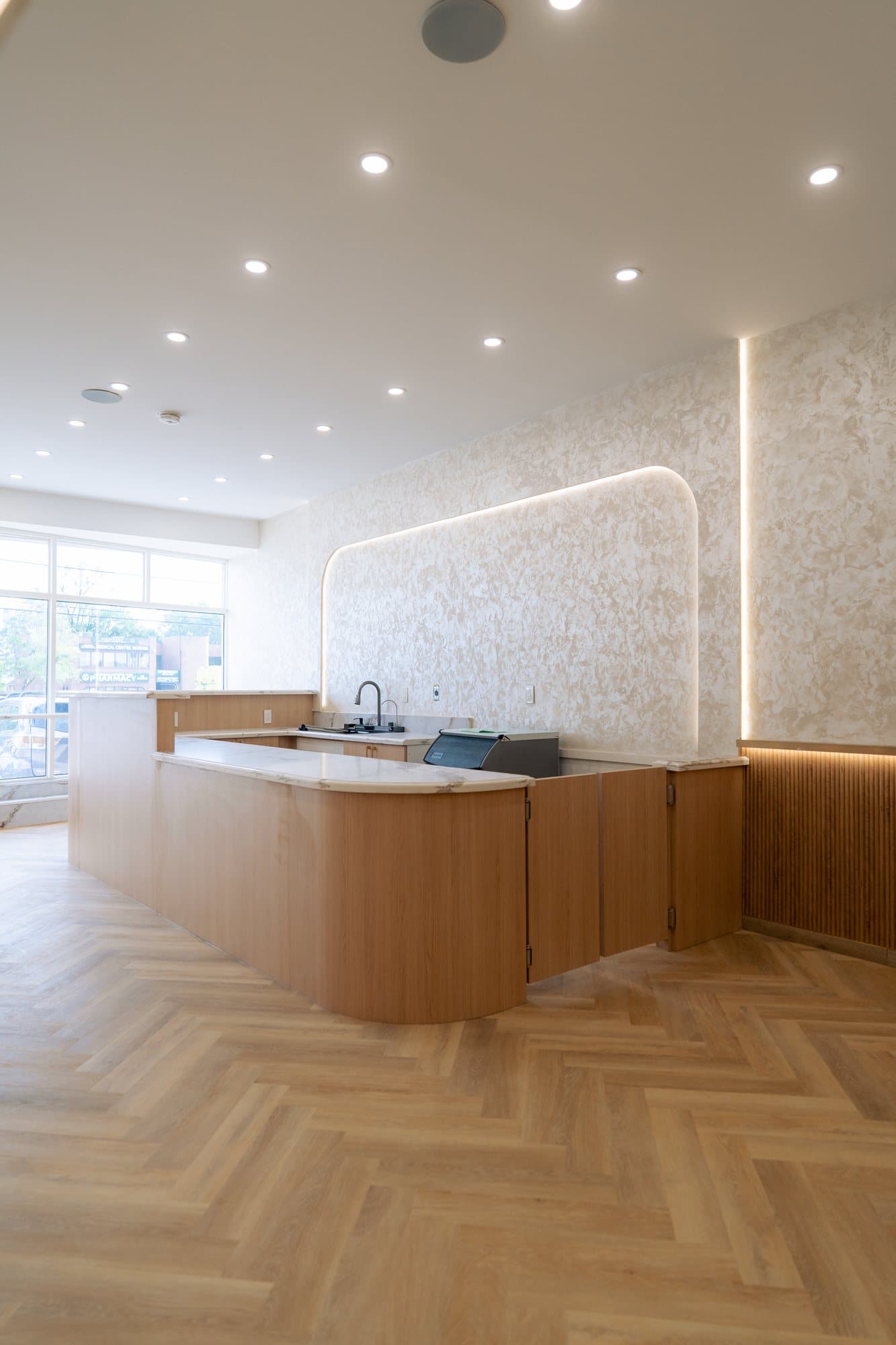 Finished cafe interior with a curved oak service counter and herringbone floor, Toronto commercial renovation