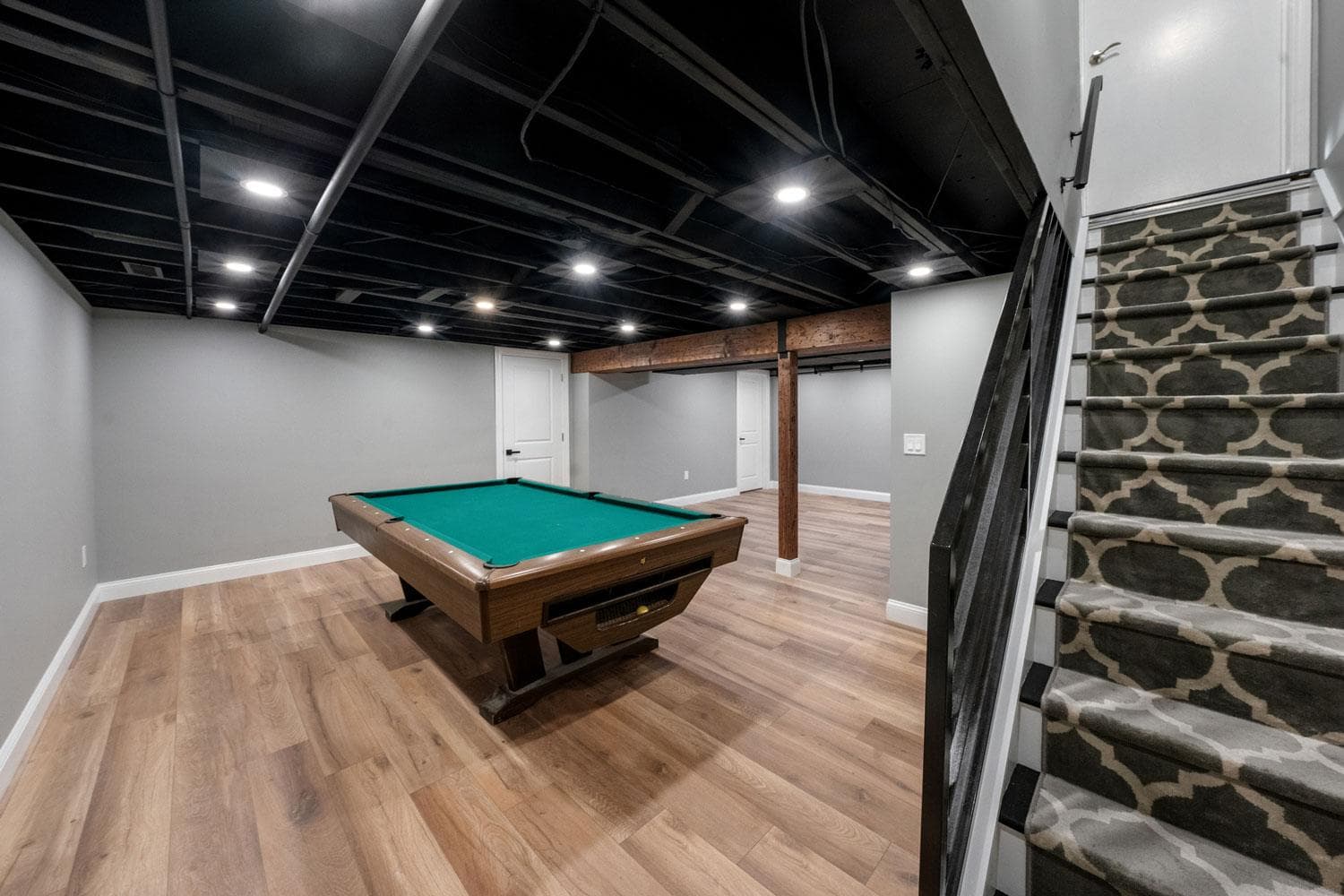 The finished basement rec room with flat walls and engineered plank flooring