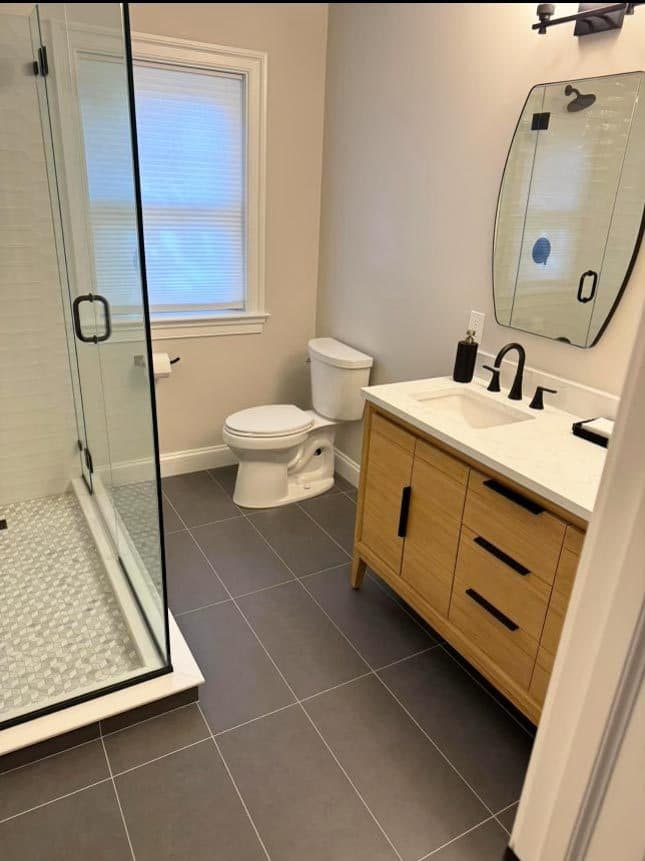 The finished bathroom with a frameless glass shower and a floating vanity