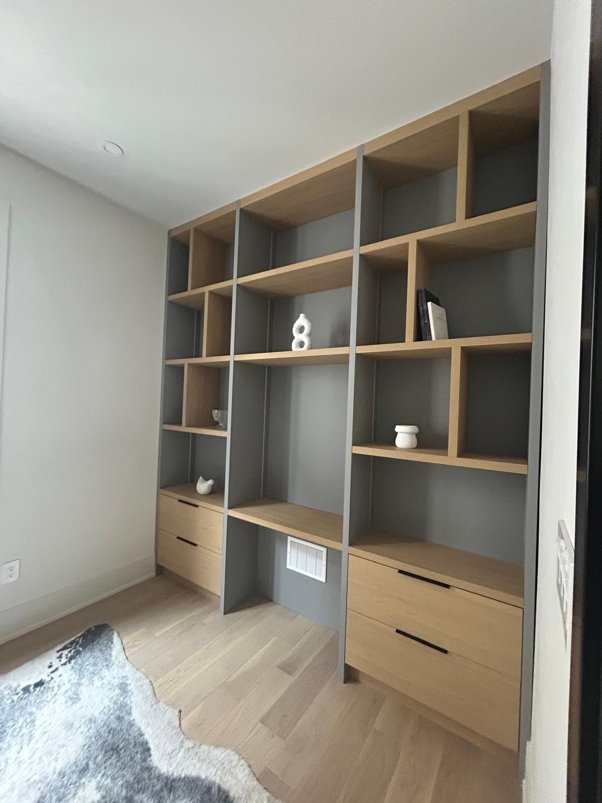 Floor-to-ceiling built-in shelving in white oak and grey lacquer