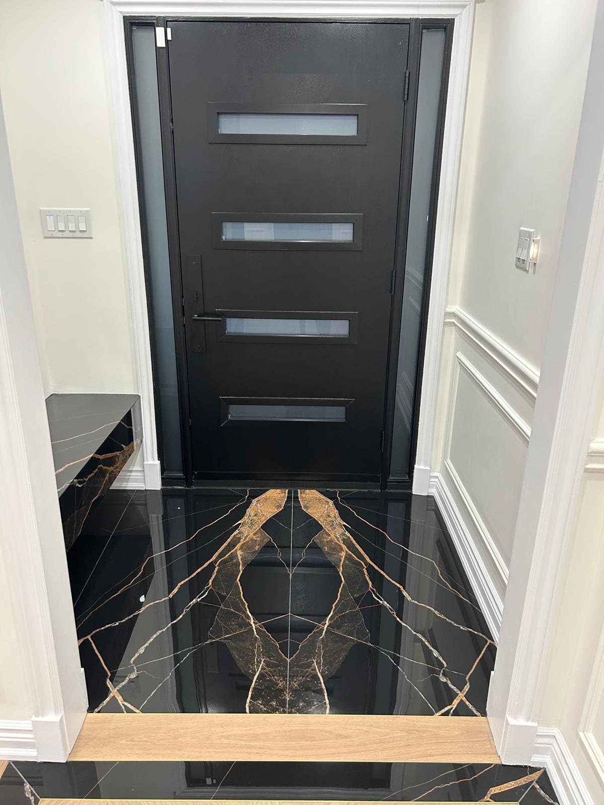 Entry floor in black and gold marble slab framed by a white oak threshold
