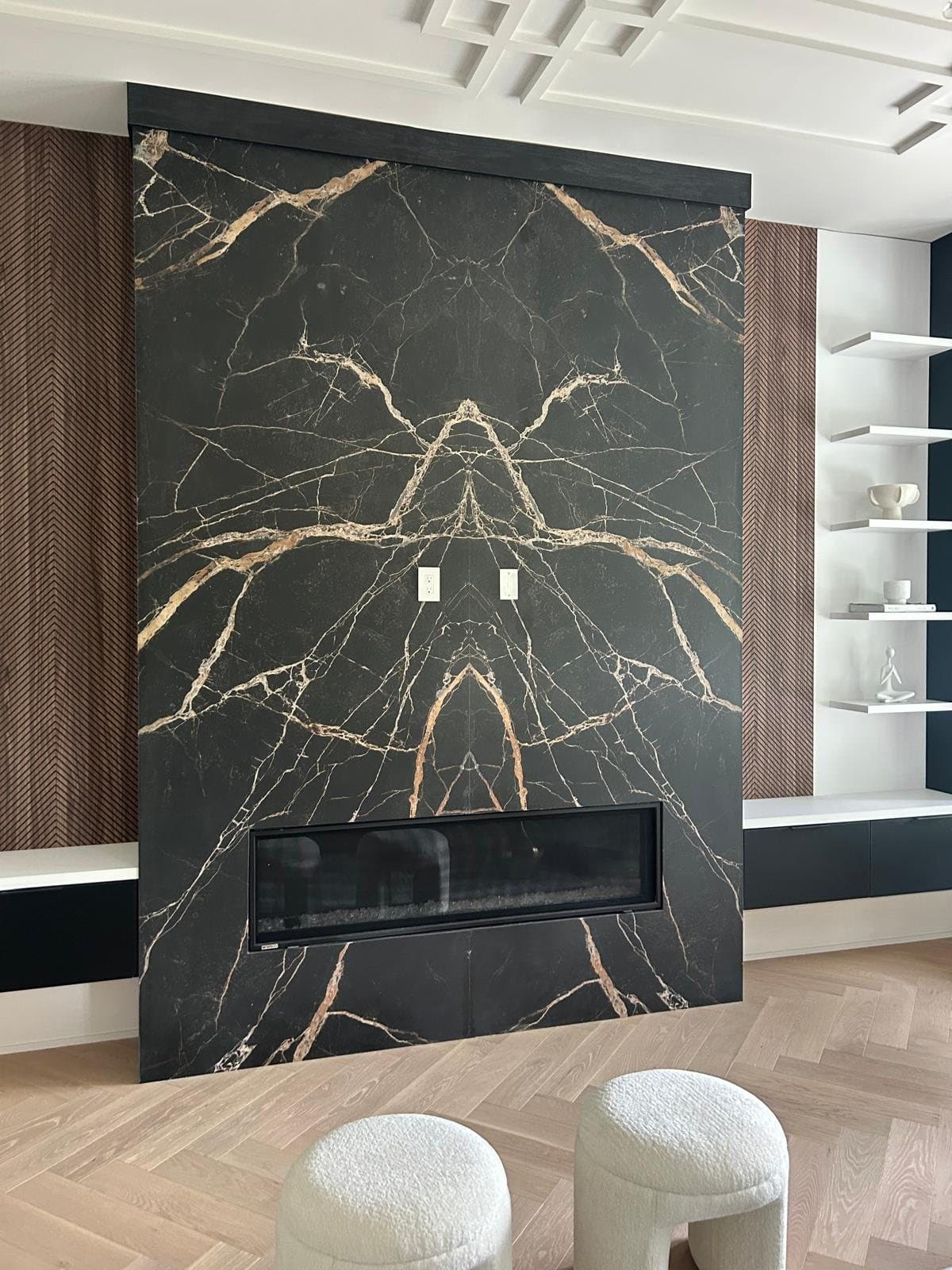 Book-matched black marble fireplace wall flanked by walnut millwork, Toronto stone and slab installation