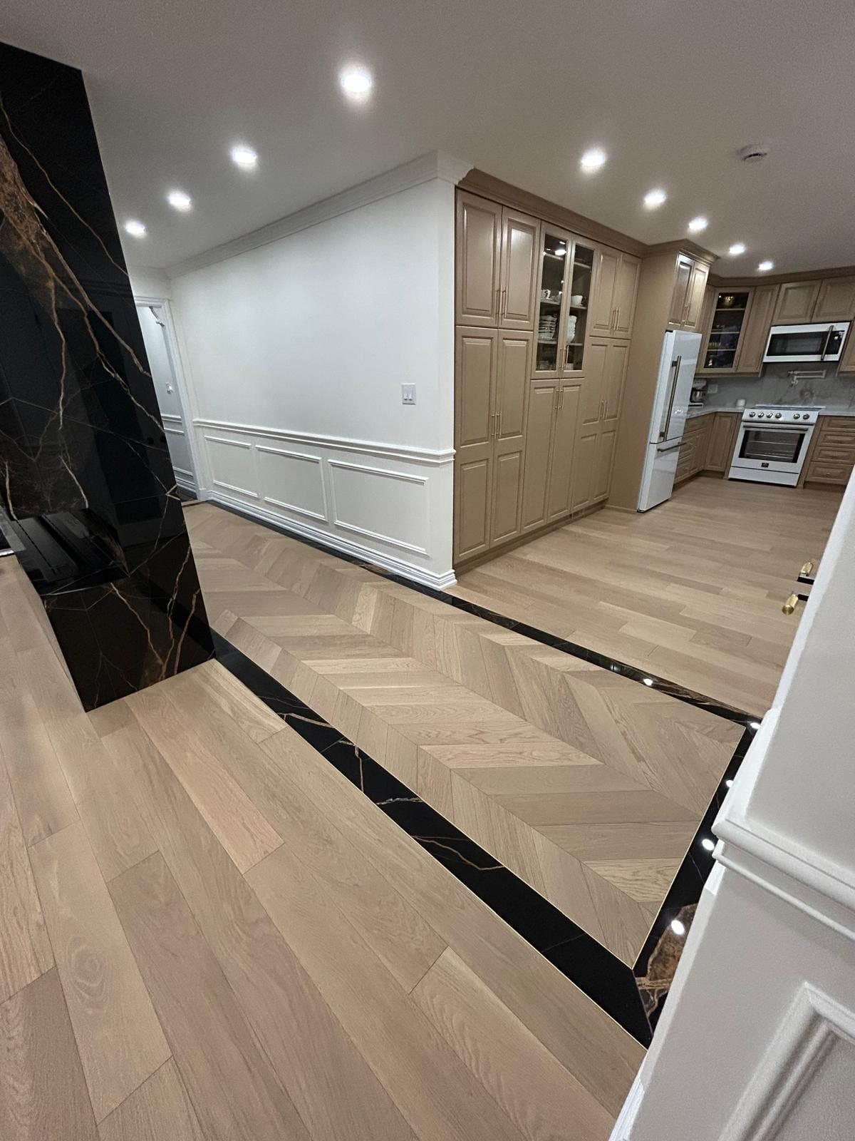 The finished chevron oak running from a panelled hallway into the kitchen