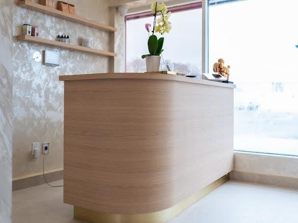 Curved white oak reception desk on a brass plinth