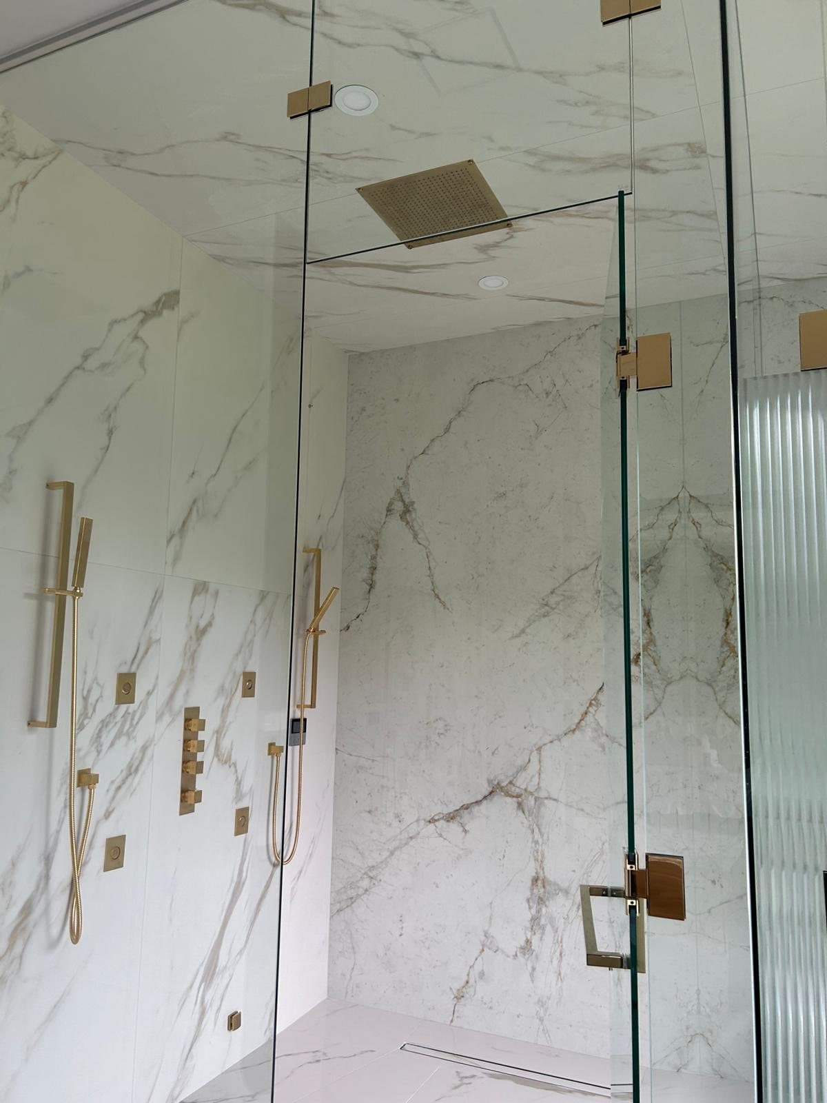 Calacatta slab shower with unlacquered brass fixtures and a frameless glass door, Toronto bathroom renovation